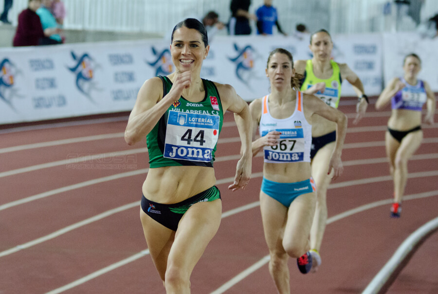Grupo de mujeres corriendo en pista cubierta de atletismo